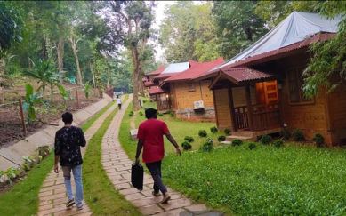 Guests walking along the pathway between cottages at The Woods Resort Maredumilli