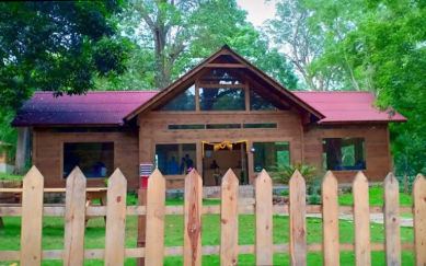 Wooden cottage behind a picket fence at The Woods Resort Maredumilli