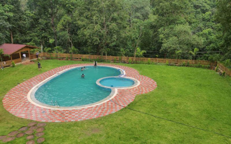 Aerial view of the swimming pool and lawn at The Woods Resort Maredumilli