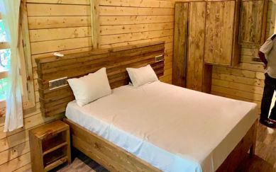Wood panelled bedroom with double bed at The Woods Resort Maredumilli