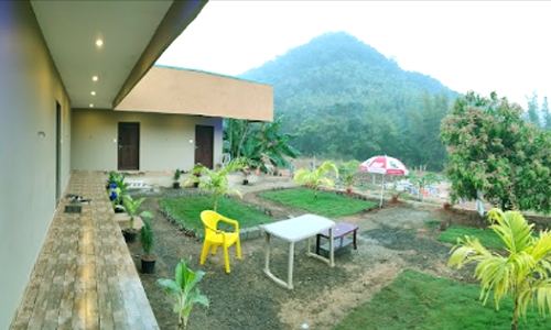 Rooms and garden at Sana Resort Maredumilli with hills behind