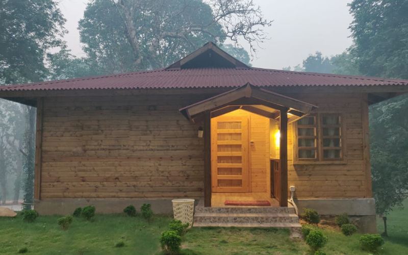 Wooden cottage at The Woods Resort Maredumilli on a misty morning